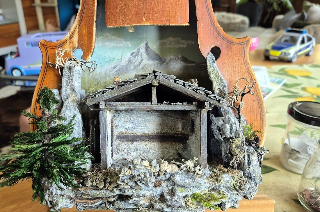 Der Stall steht in der Geige, mit gemaltem Bergpanorama, Felsen und Tanne