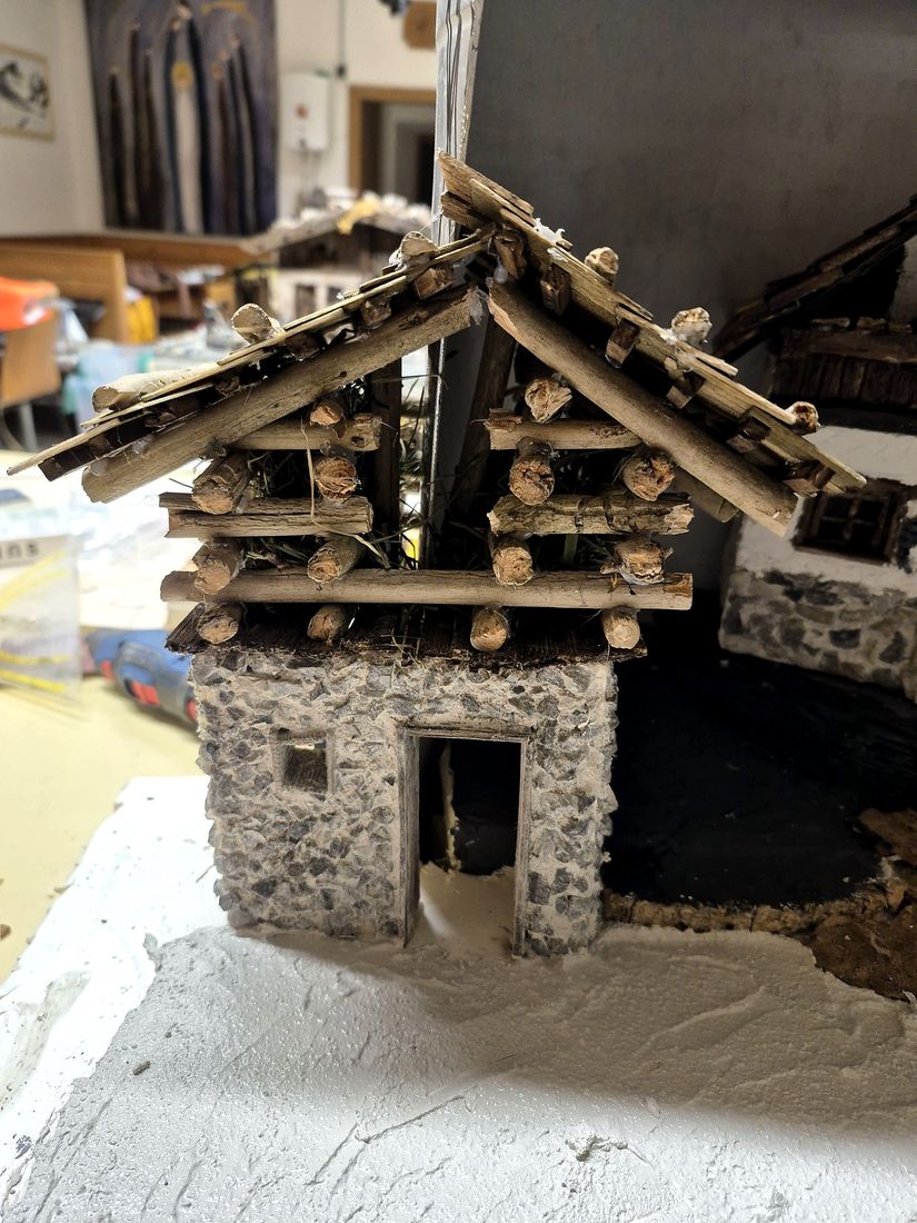 Der Stall aus Stein mit Holzstämmen unter dem Dach